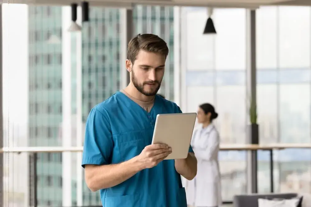 A male nurse using a tablet to check ACGME requirements online.